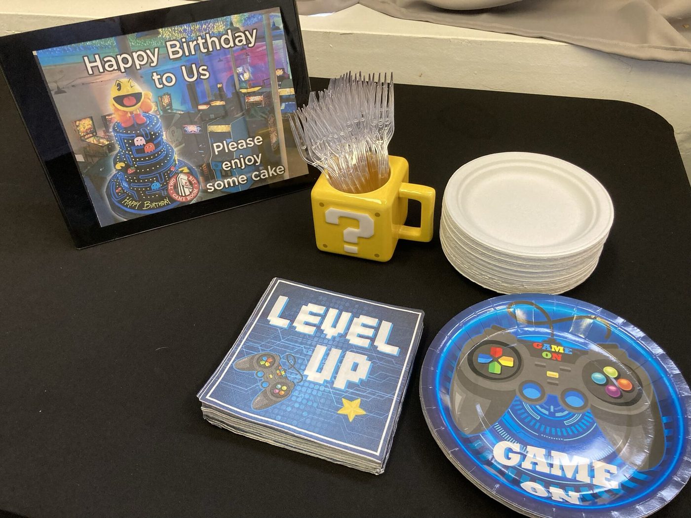Level Up napkins, game controller plates and a question-block mug on a party table