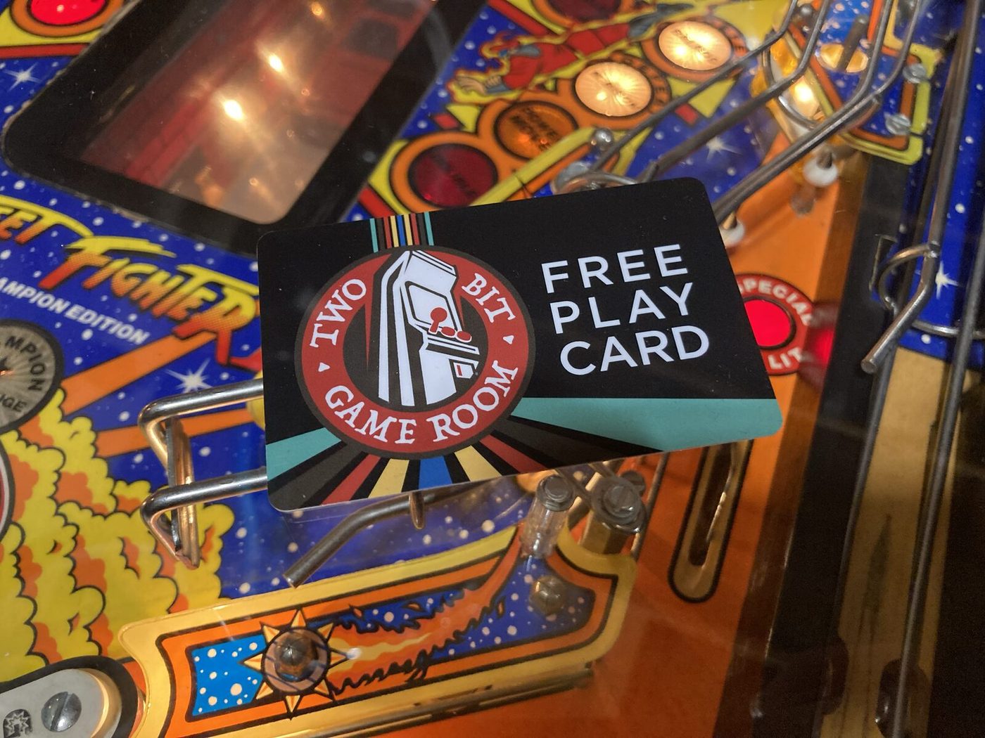 Two Bit Game Room Free Play Card on a pinball playfield