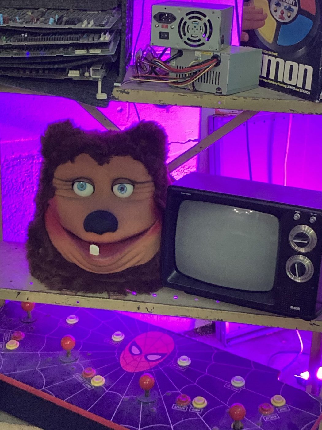 Billy Bob animatronic head from The Rock-afire Explosion beside a vintage TV under purple light