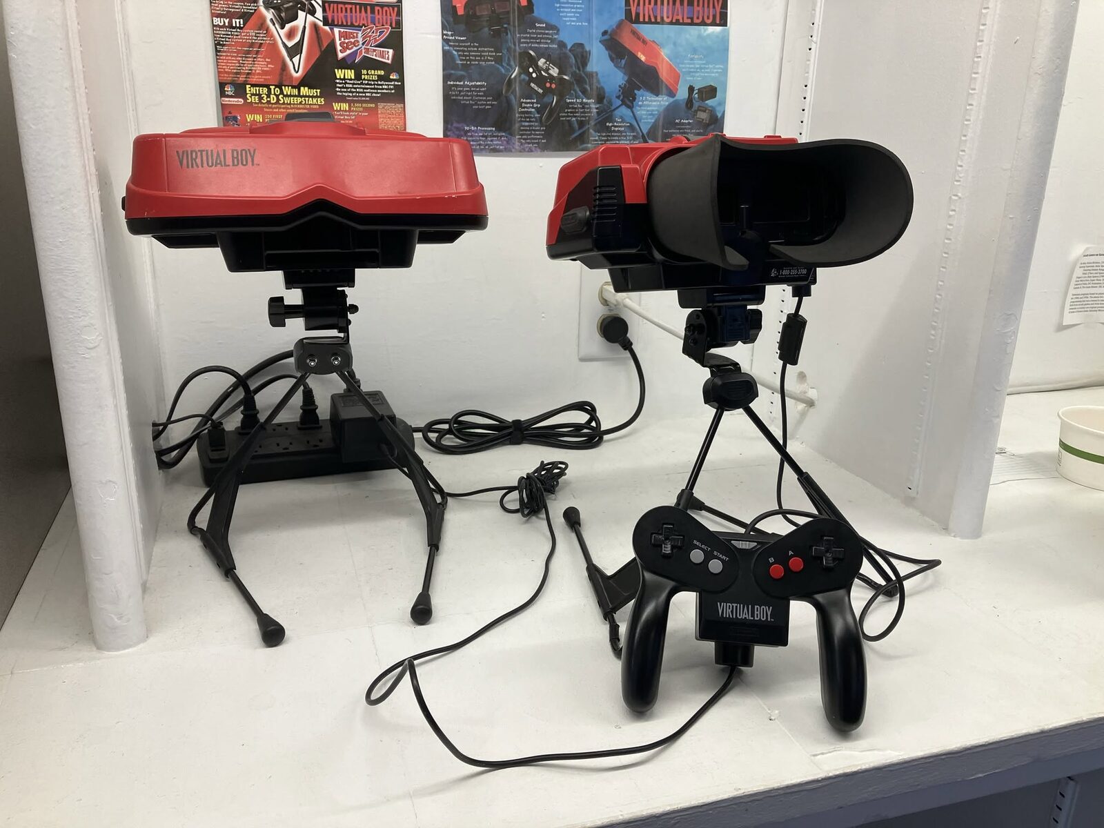 Two Nintendo Virtual Boy systems on stands with controllers
